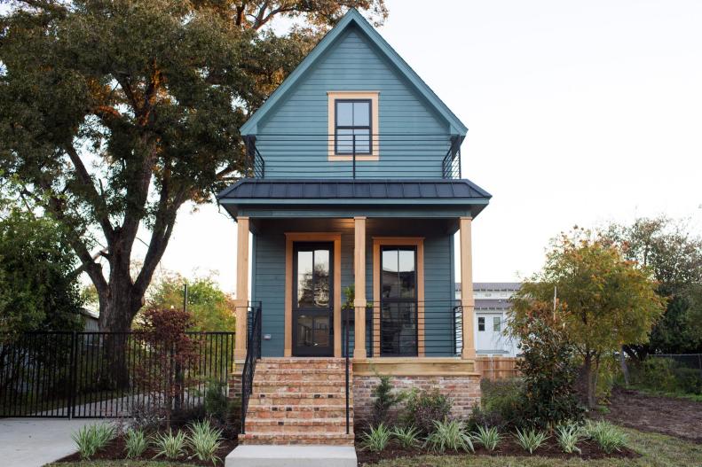Dark Green Shotgun Style Home with Metal Roof, Brick Skirt and Iron Railings