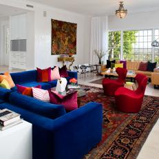 Colorful Eclectic Living Room With Royal Blue Velvet Sofa, Mixed Throw Pillows and Modern Red Chairs 