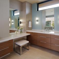 Clean, Modern Bathroom With Pastel Blue Subway Tile Accent Wall, Woodgrain Cabinets and White Seat Vanity Stool