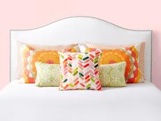 White Studded Headboard With Orange And Green Pillows