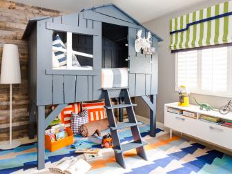 Navy loft bed, wood panel wall, and colorful rug in boys bedroom.