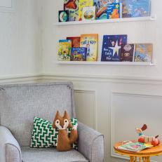 Book Display Shelves and a Soft Gray Armchair and Ottoman Complete an Inviting Reading Corner