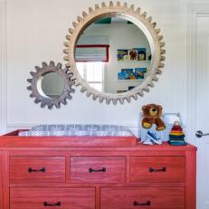 Wood Gear Mirrors Adorn the Wall Above a Red Stained Dresser and Changing Table