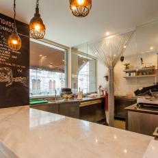 Stylish Restaurant Butcher Shop With White Marble Countertop, Beaded Doorway Decor and Warm Glow Pendant Lights