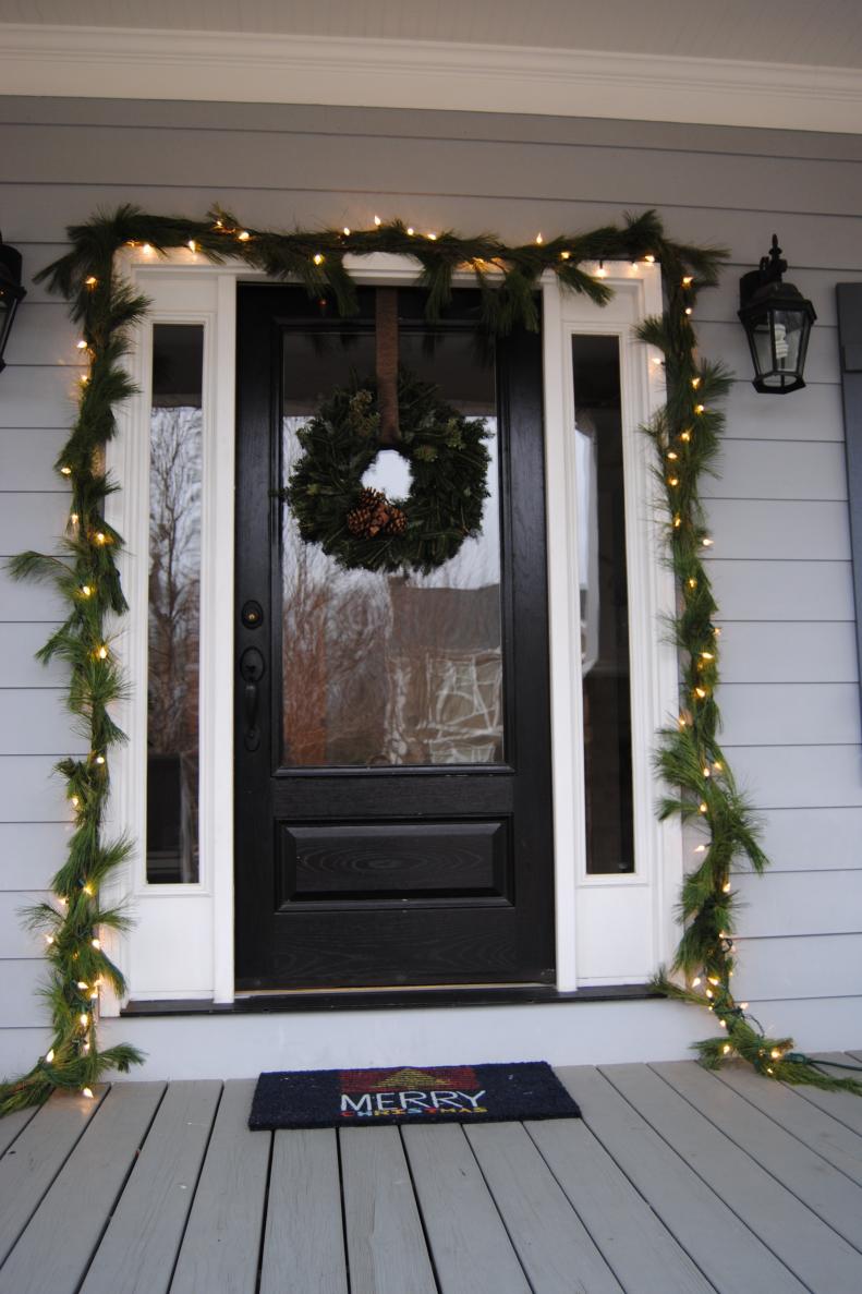 After: Garland frames the glass-front door and sidelights. To make it heavy enough to have an impact at the front door, our friend and decorator Ashley Aquino combined two white pine garlands from Trader Joe's ($6.49 for each 20-foot garland), and wrapped lights around the greenery. Three nails at the top of the door frame hold the garland in place. The welcome mat was 60 percent off last year at Target.