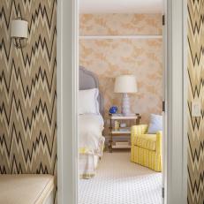 Patterned Wallpaper and marble Tile Floor Bathroom With View of Transitional Bedroom Featuring Yellow Accent Chair