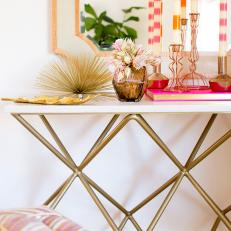 Close Up on Contemporary Table Featuring Gold Geometric Leg Design, White Tabletop and Orange Framed Mirror 