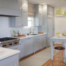 Spacious Transitional Kitchen with Gray Cabinetry, Chevron Backsplash and Eat In Island With Marble Countertop 