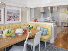 Sunny Cottage Dining Room With Yellow Tufted Leather Bench, Contemporary Wood Dining Table and Connected Kitchen 