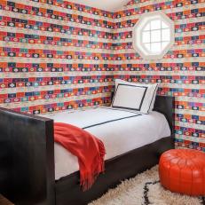 Contemporary Bedroom With Colorful Penguin Books Wallpaper, Black Twin Bed Frame, and Orange Leather Floor Pillow