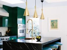 White and Green Kitchen With Gold Pendant Lights and Black Countertops
