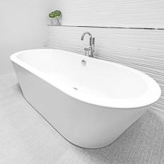 Modern White Bathtub Against Textured White Accent Wall and Light Tile Flooring 