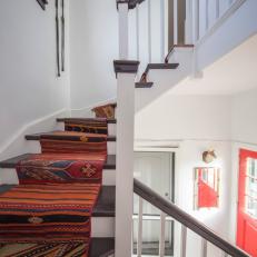 Winding Staircase With Dark Wood Steps and Matching Railing and Bold, Colorful Southwestern Runner