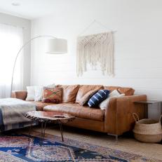 Bohemian Style Contemporary Living Room With White Ship Lap Wall, Brown Leather Sectional and Macrame Wall Hang 