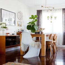 Bright Contemporary Dining Room Featuring White End Chair With Faux Fur Cover and Polished Hardwood Floor 