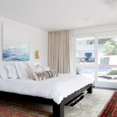 Modern Master Bedroom With Colorful Patterned Rugs, Sliding Glass Door and Black Bed Frame 