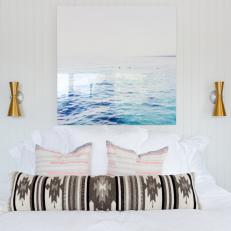 Modern Bed Decor With Bohemian Throw Pillows, Plexiglass Sea Photo and Gold Sconces 