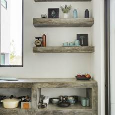 Gray Stone Kitchen Countertop and Shelf Structure With Matching Floating Shelves Over White Wall 