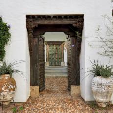 Asian Front Entryway With Elaborate Door Frame, Cobblestone Walkway and Large, Distressed Vases