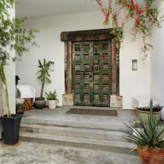 Asian Front Door With Distressed Framework, Green Grate Design and Faded Red Coloring at Stone Front Porch 