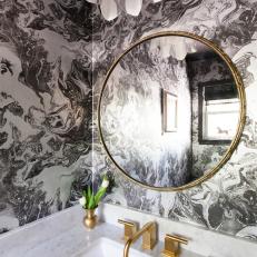 Black and White Marble Powder Room With Brass Faucet and Mirror Frame Above White Marble Countertop 