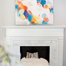 Chic Fireplace With Colorful Art and Faux Fur Stool