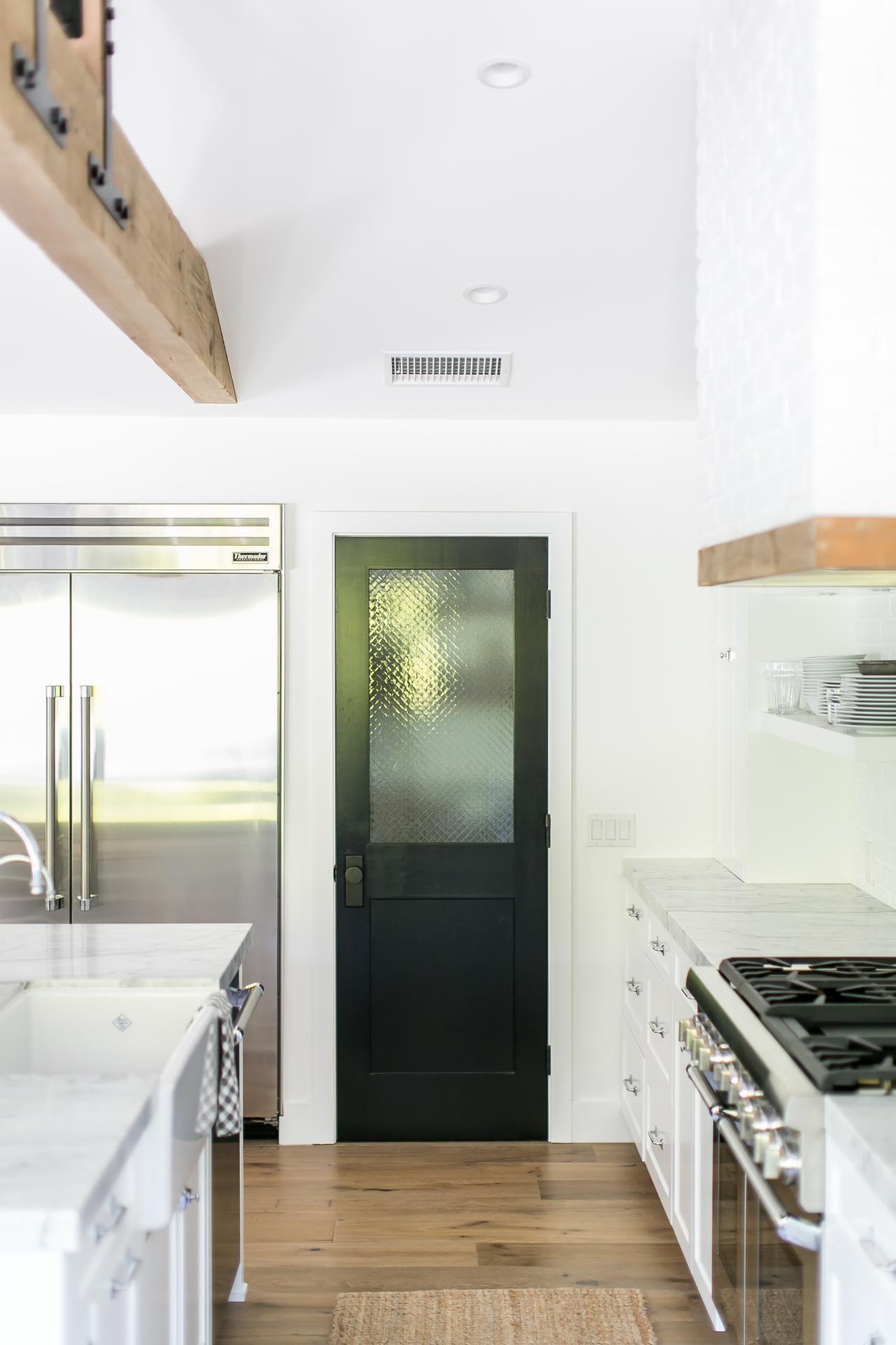 Black Pantry Door In Bright White Kitchen With White Marble