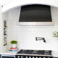 Black and Stainless Steel Stove and Oven With Matching Surrounding Cabinets and Matching Range Hood Under White Frame