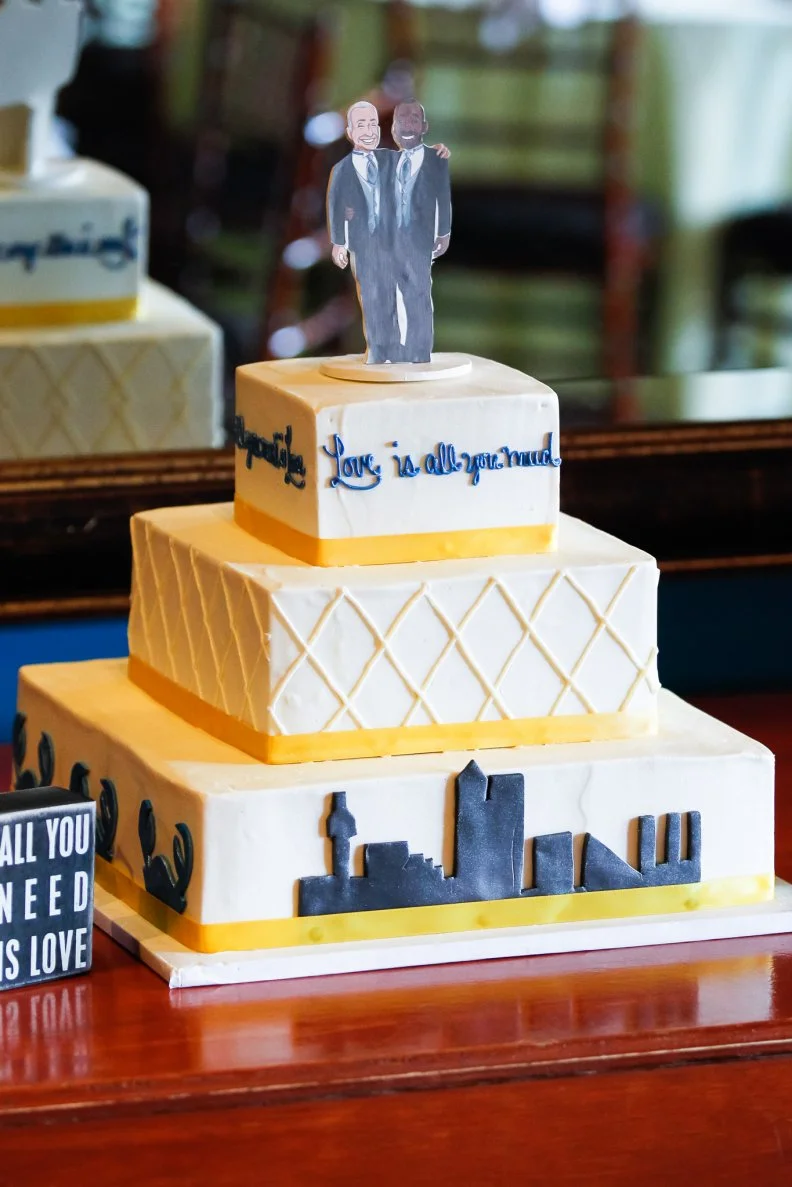 Paper Cutout of Two Grooms on Top of White Wedding Cake