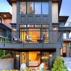 Brick Urban Home Exterior With Black Iron Rail Balcony Over Concrete Ground Level Porch 