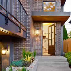 Urban Brick Home Exterior With Concrete Step Walkway, Built In Planters and Wood Front Door 