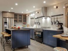 As seen on America’s Most Desperate Kitchens, this Atlanta, Georgia home features a newly renovated kitchen by John Colaneri and Anthony Carrino. Renovations to this kitchen included removing a wall that divided the kitchen along with a window to redesign the layout of the kitchen. Custom baskets were hung on the wall for more storage, made from 100 year old reclaimed barn wood. Cold war steel floating island on casters, bring more counter space, stoarge and seating. High hat lights on dimmers for task lighitng throughout kitchen along with a geometically chandelier and School House lighting fixtures. Grey cerused oak finishing techinque on cabinets to bring in a old world feel.  Reclaimed barn wood framing over window panels and door frames. Shiplap was used to bring texture covering the one wall. Sherwin Williams Gale Force blue-teal tone for cabinet to add color, and Walker Zinger back splash to add a modern touch to this renovation. (After)