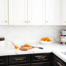 Black and White Cabinets Separated by Marble Countertop and Herringbone Backsplash in Transitional Kitchen 