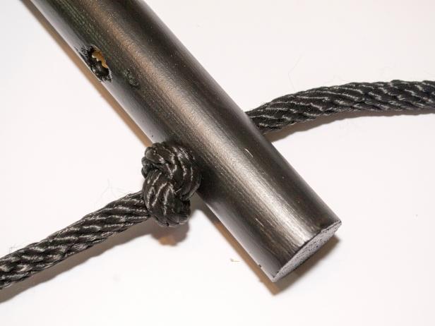 Thread the unknotted end through the one of the holes on the end of dowel. The knot should rest on top of the dowel.