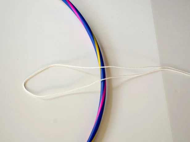 Fold one length of rope in half and lay it across one section of the hula hoop.