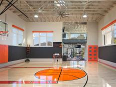 Indoor Basketball Court With Orange Accents, Charcoal and Orange Wall Pads and High Beamed Ceilings 