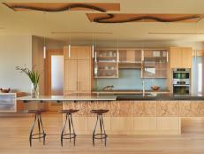 Open Modern Kitchen With Decorative Island Wood Accent Finish, Frosted Glass Cabinets, and Track Pendant Lighting 