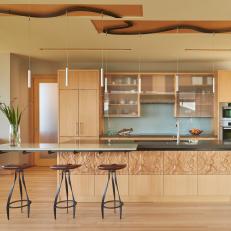 Open Modern Kitchen With Decorative Island Wood Accent Finish, Frosted Glass Cabinets, and Track Pendant Lighting 
