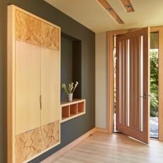 Modern Entryway With Built In Cabinet Featuring Decorative Wood Finish, Wall Cut Out With Storage Containers and Striped Panel Door
