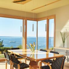 Sunny Contemporary Dining Room With Track Pendant Lighting, Woven Brown Seats on Wood Chairs and Modern Dining Table
