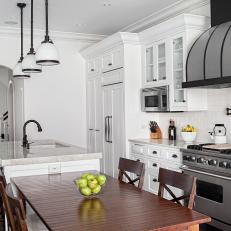 Timeless Traditional Kitchen With White Tile Backsplash, Black Framed Range Hood and Wood Dining Set Up