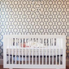White Baby Crib and Mobile Against Gray and White Wallpaper