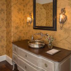 Warm, Traditional Vanity Space With Mustard Yellow Floral Wallpaper, Distressed Vanity Base and Stainless Steel Vessel Sink 