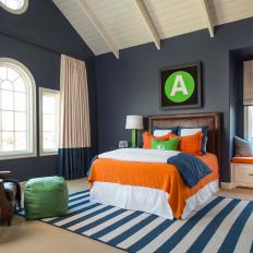 Spacious and Bold Teen Bedroom With Bright Orange and Green Accents Against Dark Blue Walls 