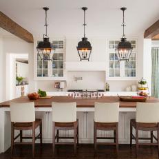 Lantern Pendant Lights Over Large Eat In Kitchen Island With Wood Countertop and Wood Chairs With Neutral Back Slip Covers
