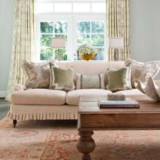 Neutral Sofa With Ruffled Bottom and Wood Coffee Table With Decorative Legs in Shabby Chic Living Room 