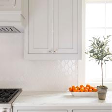 White Kitchen Quartz Countertop and Built in Cabinets Surrounding Diamond Shaped Tile Backsplash 