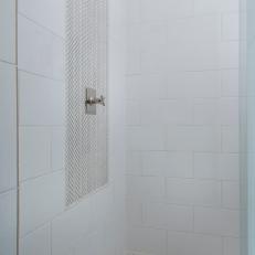 White Shower Featuring a Tile Accent Panel Framing the Shower Head and a Penny Tile Floor 