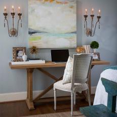 Watercolor Painting and Vintage Candle Light Fixtures Over Stylish Desk Set Up With White Upholstered Wood Chair