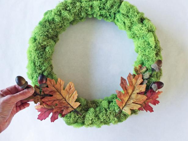 Craft a cheery touch of fall for your front door with a moss-covered wreath form and autumnal ribbon roses.